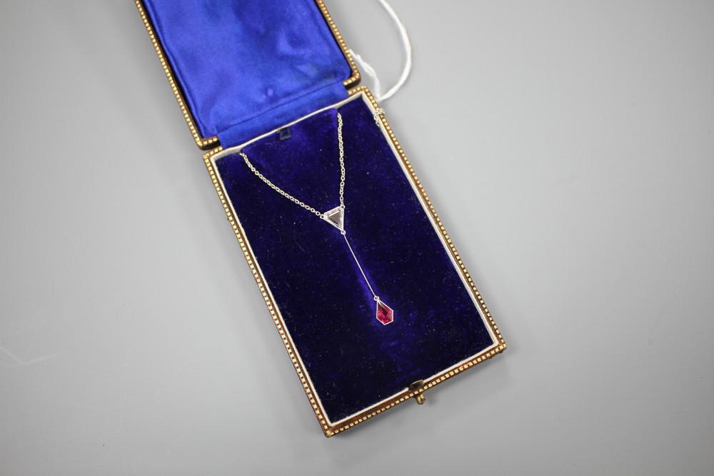 An Art Deco style white metal, ruby and diamond set drop pendant necklace, pendant section 40mm, gross weight 3.9 grams.